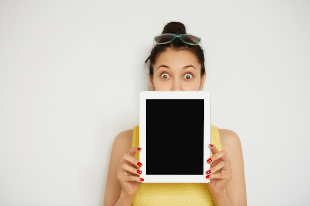 Selective focus. Close up view of digital tablet with copy space for your text or advertisement. Cropped isolated portrait of surprised young brunette woman looking out of the blank tablet computer ** Note: Soft Focus at 100%, best at smaller sizes